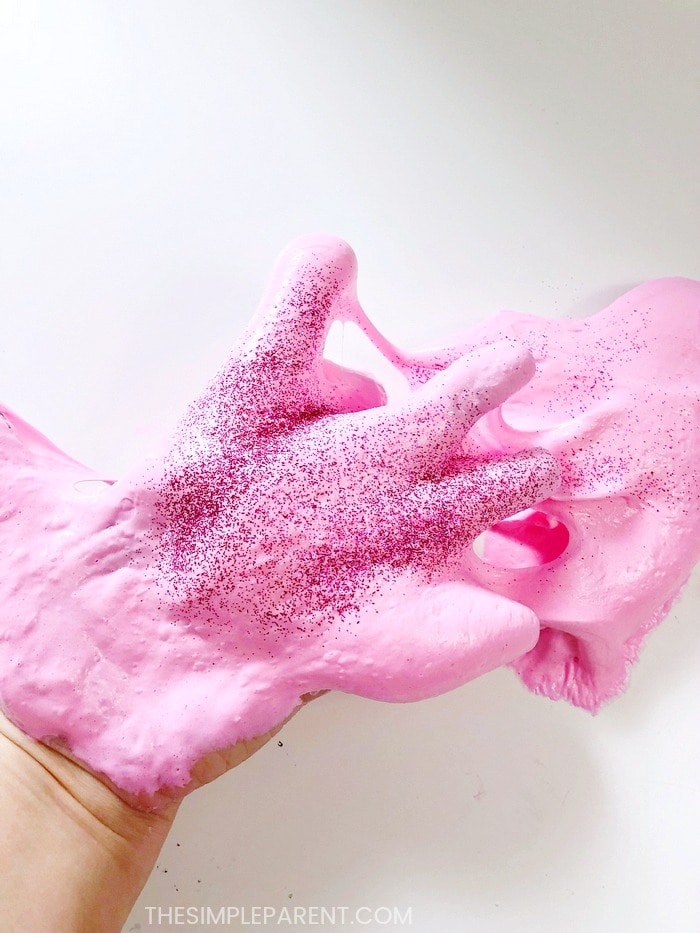 Adding glitter to pink fluffy slime to make it sparkle!