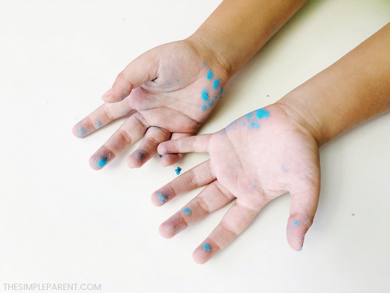 Blue kinetic sand on child's hands