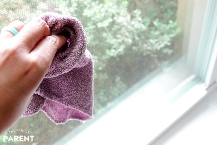 Cleaning windows with purple rag to get nose prints and fingerprints off is one of the easiest spring cleaning tips