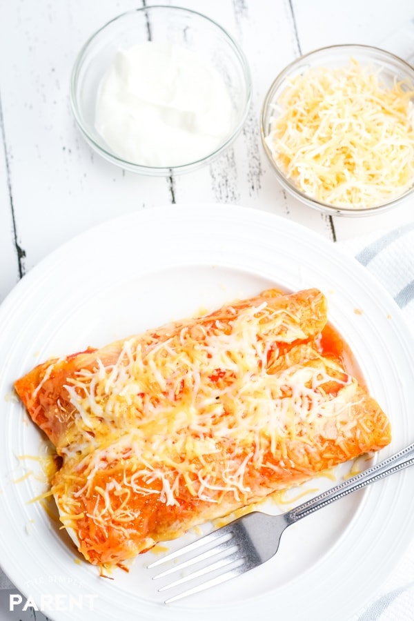 Plate of Crock Pot chicken enchiladas with sour cream and shredded cheese