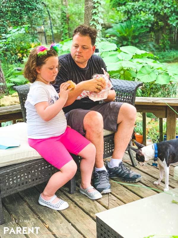 Dad and daughter eating a sandwich together on back deck