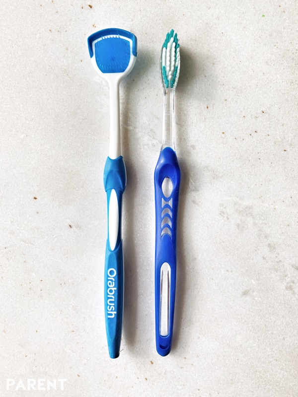 Orabrush Tongue Cleaner and a toothbrush on the bathroom sink