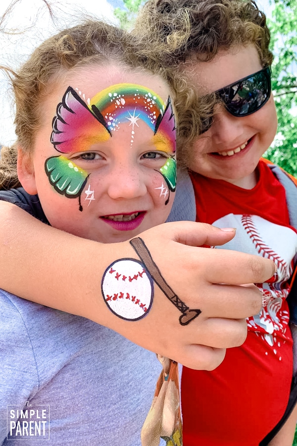 Brother and sister with face painting of a butterfly and a baseball