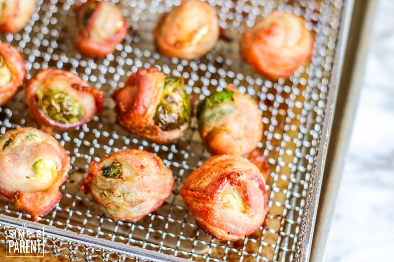Cooked Brussel sprouts wrapped in bacon in an air fryer basket