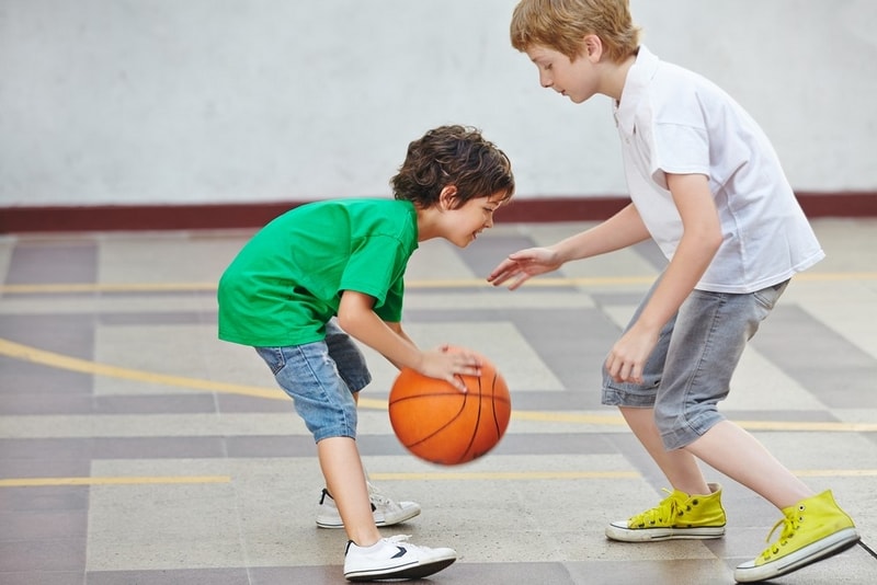 Two boys playing basketball on an indoor basketball court