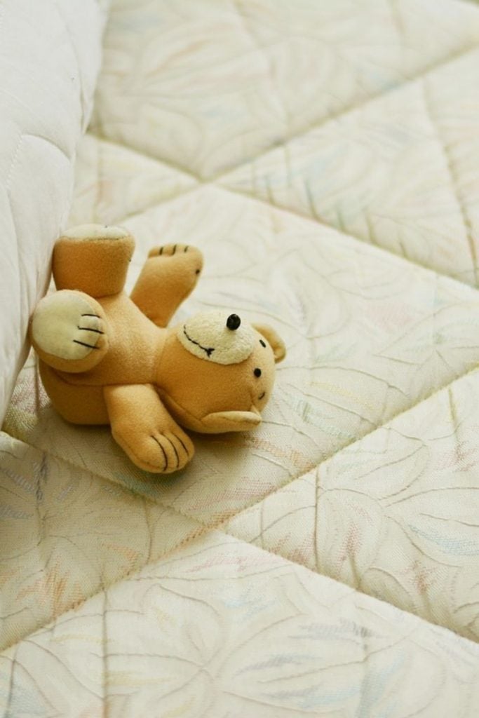 Mattress with teddy bear toy laying on top