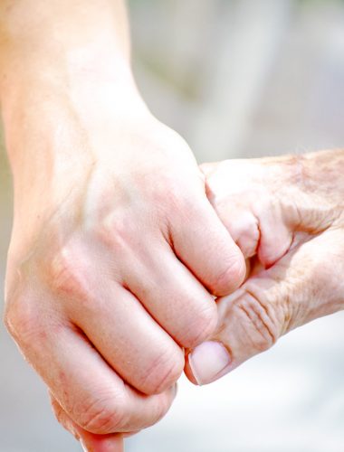 Younger person holding hands with an older adult