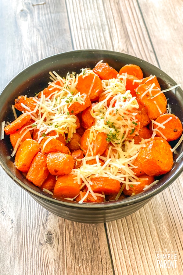 Bowl of air fryer garlic carrots topped with shredded parmesan cheese