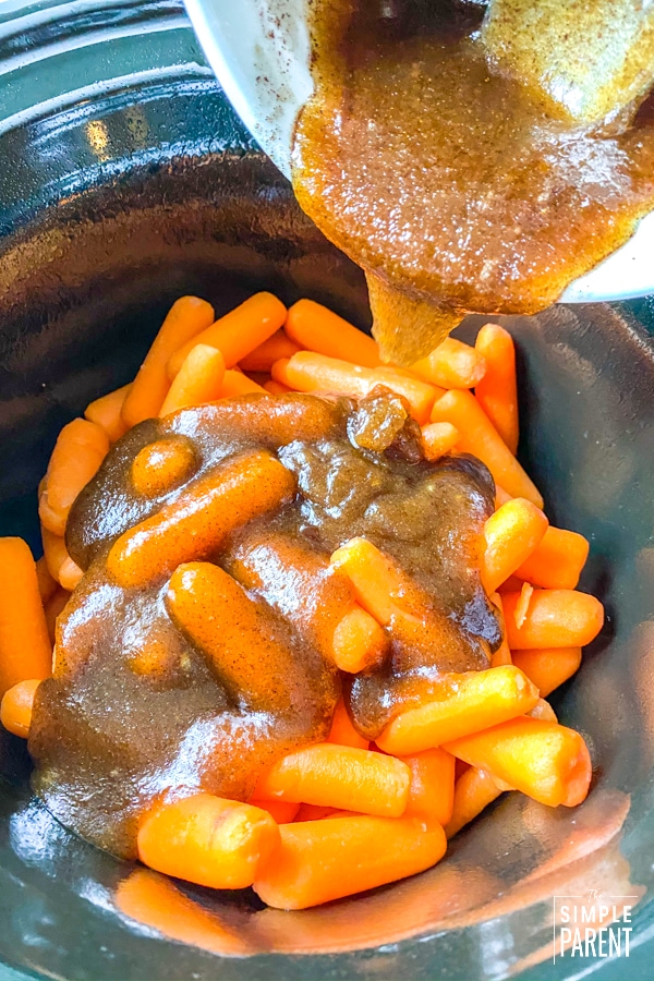 Pouring brown sugar glaze on carrots in slow cooker crock
