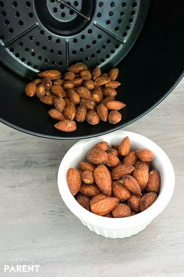 Pouring air fryer almonds into a bowl