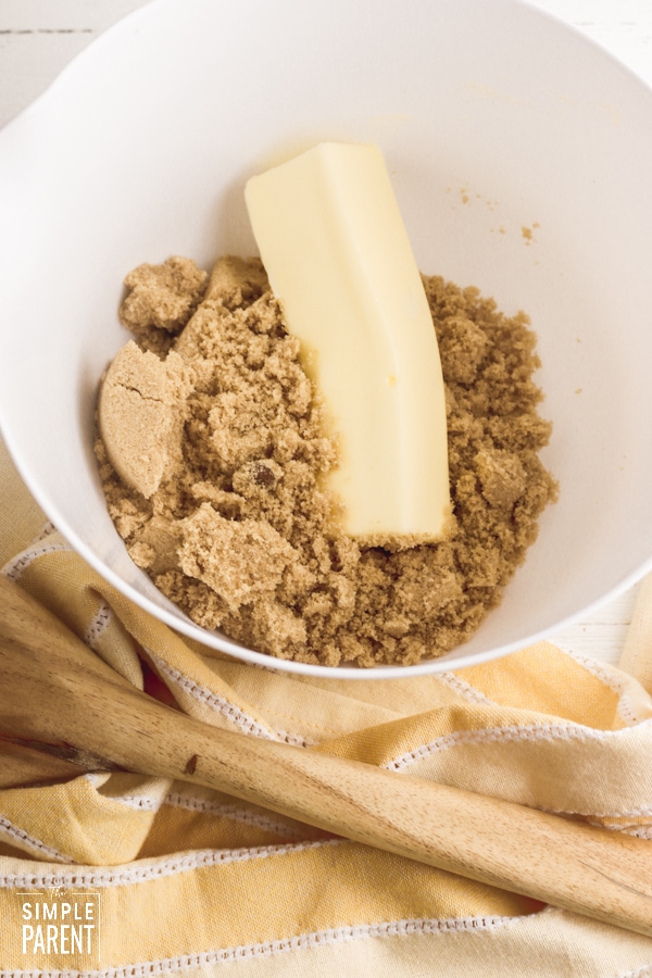 White mixing bowl with brown sugar and softened stick of butter