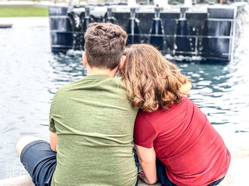 Brother and sister sitting together looking at water