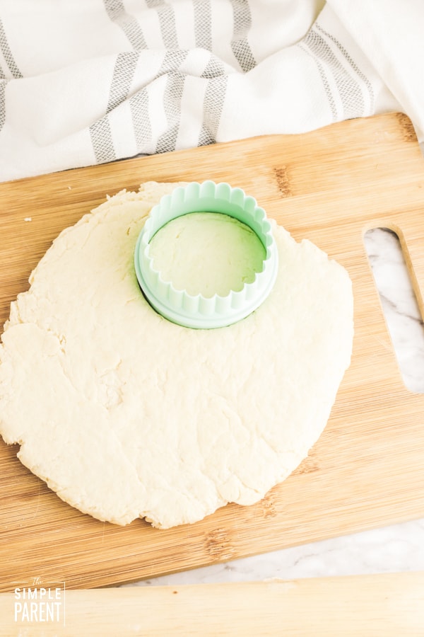 Using round biscuit cutter to cut biscuit dough