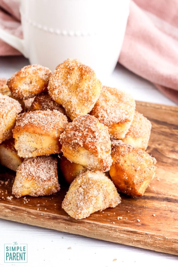 Stack of air fryer donut bites with cinnamon sugar on a cutting board