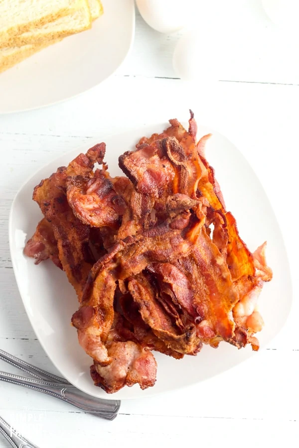 White plate with stack of bacon on it