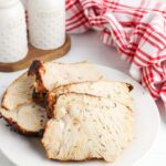 Slices of air fried turkey on white plate with red checkered napkin