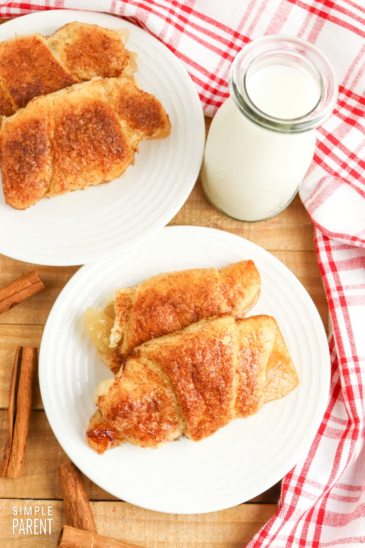 Apple crescent rolls on white plate with red and white napkin and glass of milk