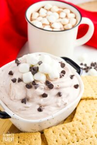 Bowl of hot chocolate dip with graham crackers and mug of hot cocoa