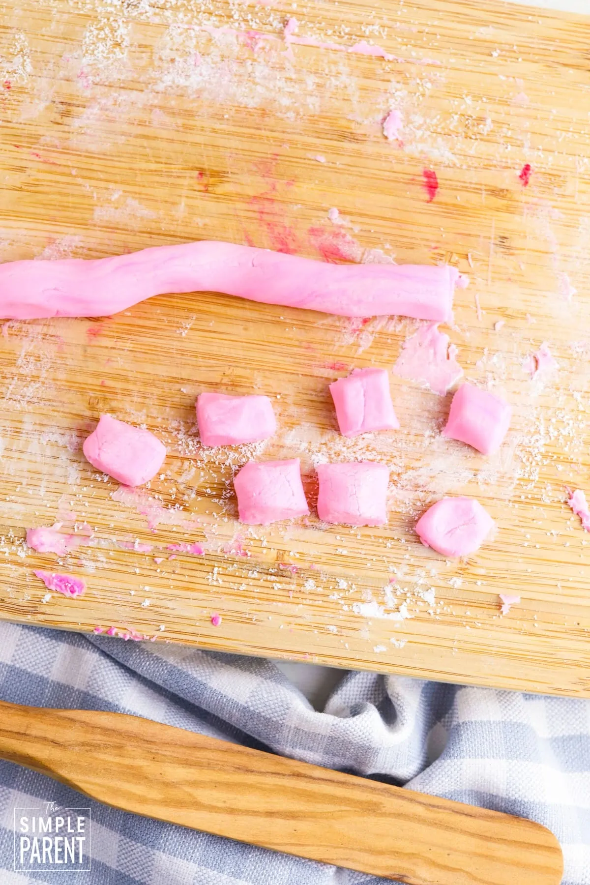 Pink butter mints dough rolled and cut into small pieces on cutting board