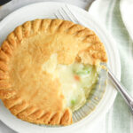 Frozen pot pie in the air fryer on a white plate with a fork
