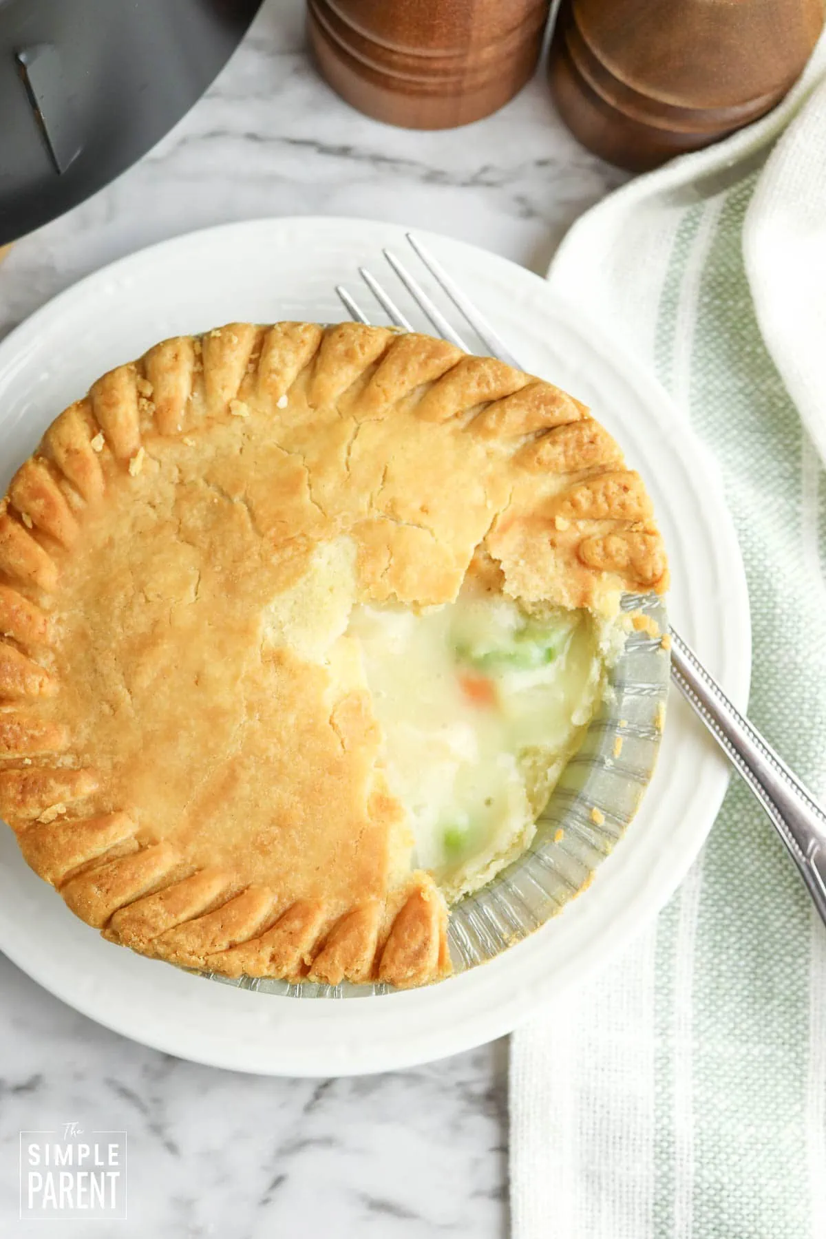Frozen pot pie in the air fryer on a white plate with a fork