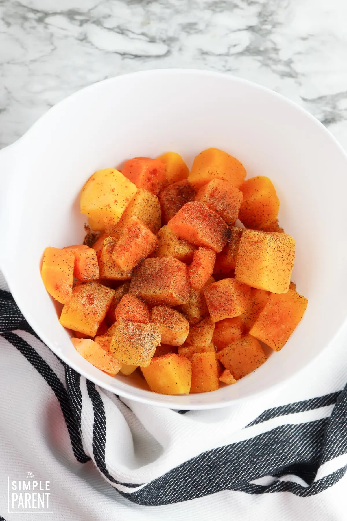 Butternut squash cubes in white mixing bowl