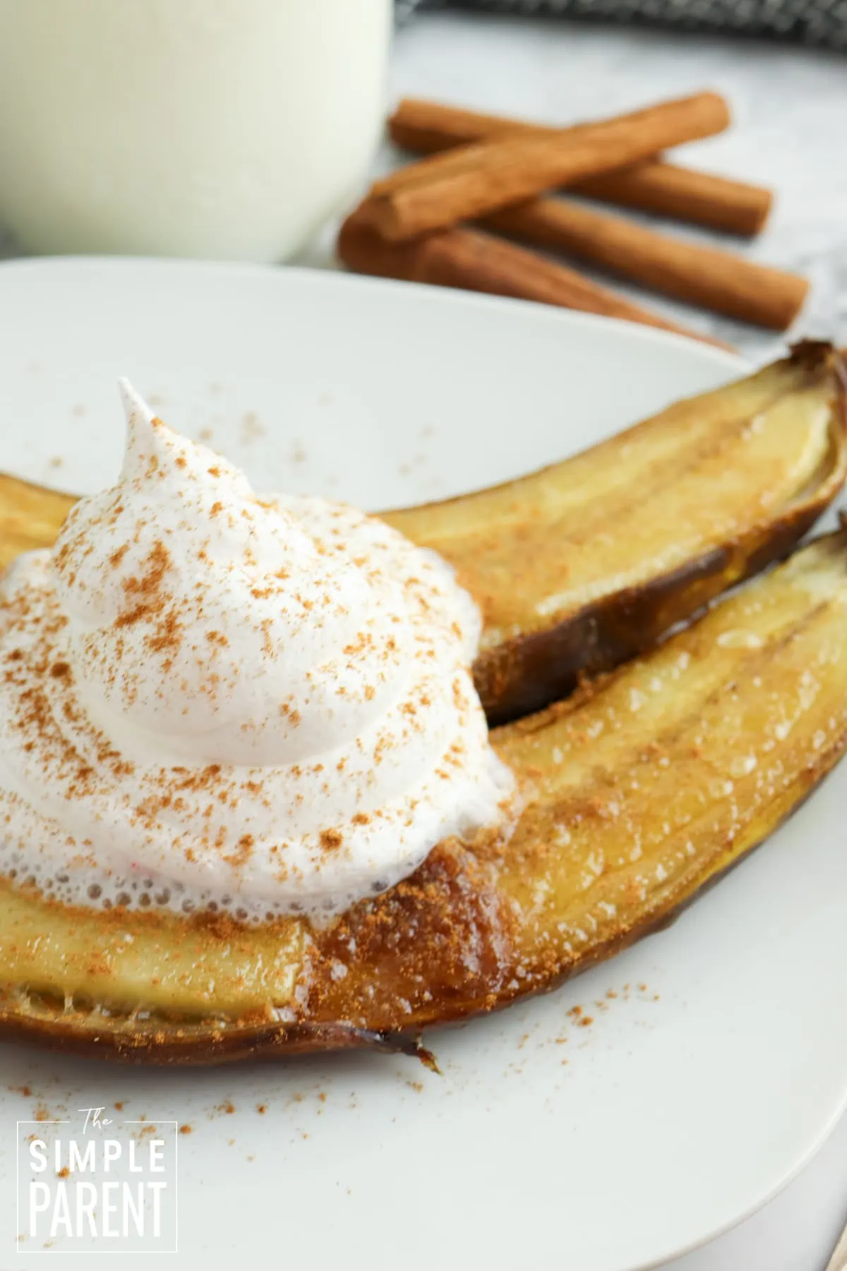 Air fried bananas on white plate with whipped cream and cinnamon