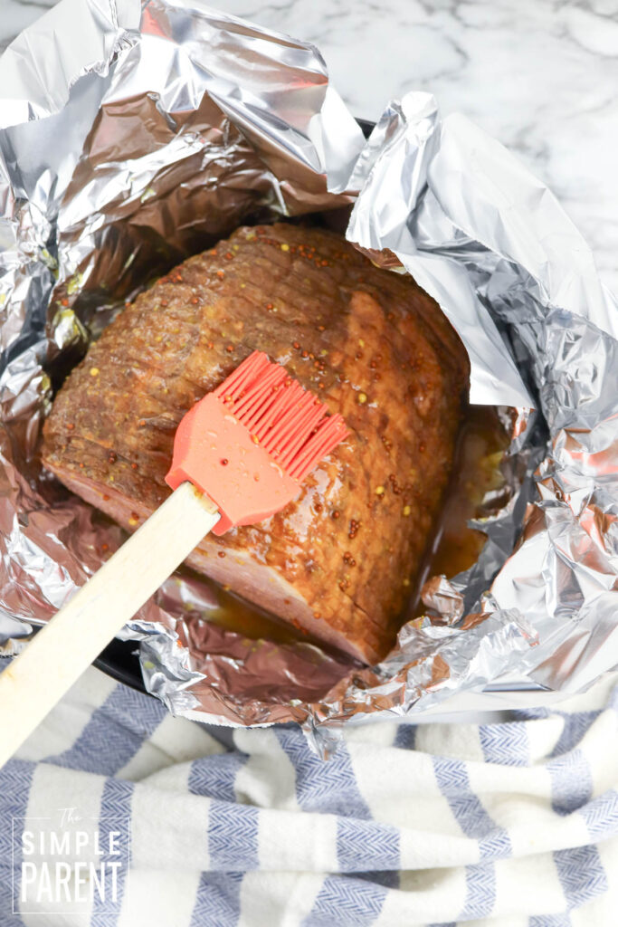 Brushing glaze on ham in foil