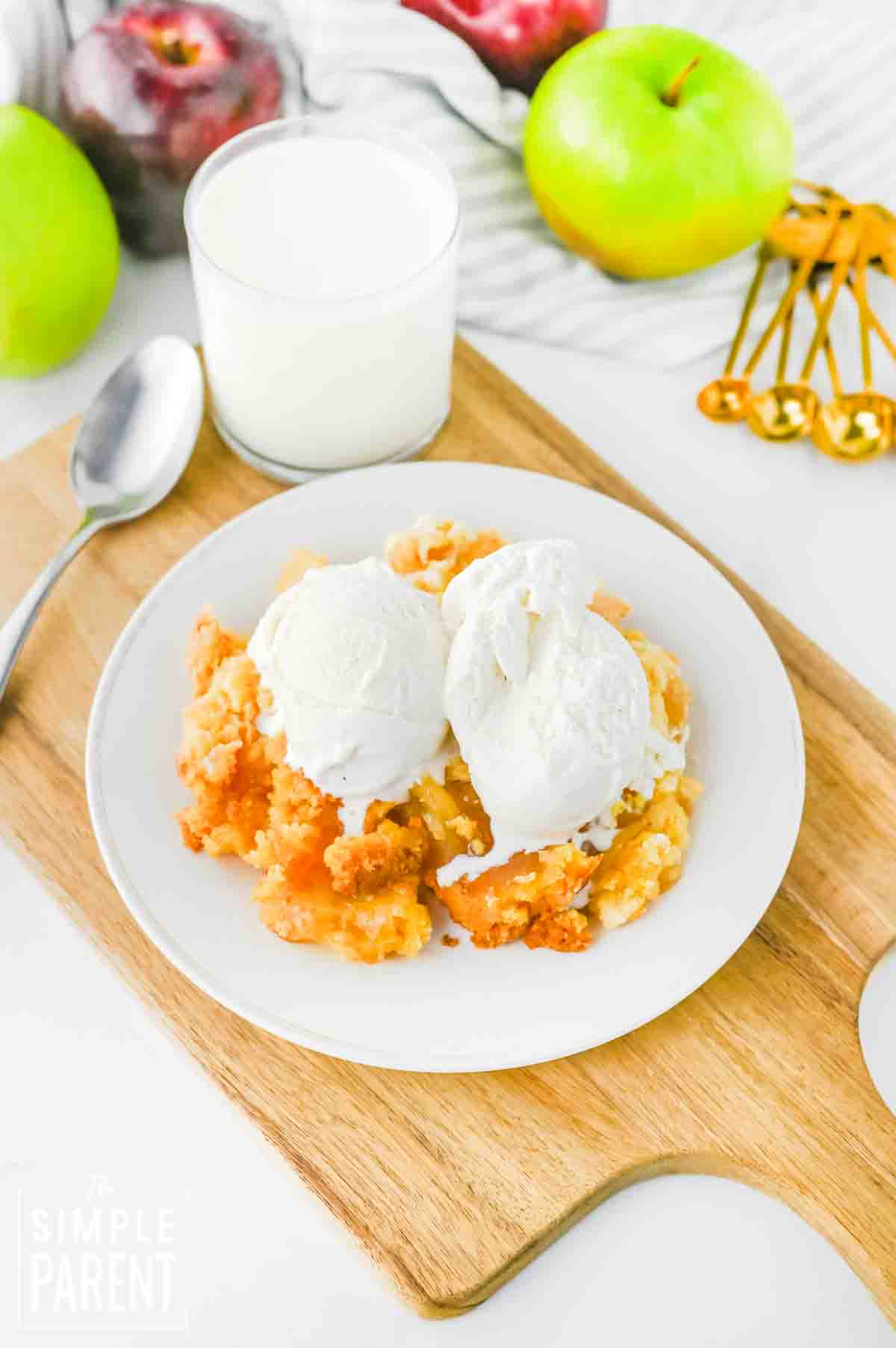 apple pie dump cake topped with vanilla ice cream on white plate