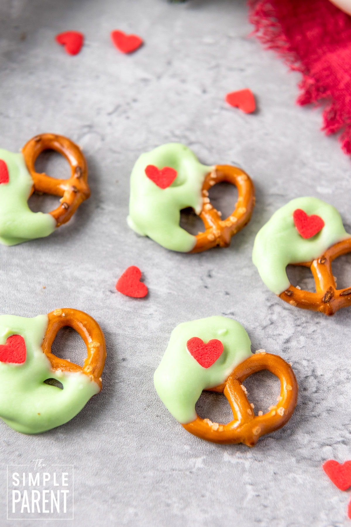 Grinch themed white chocolate covered Christmas pretzels on gray counter
