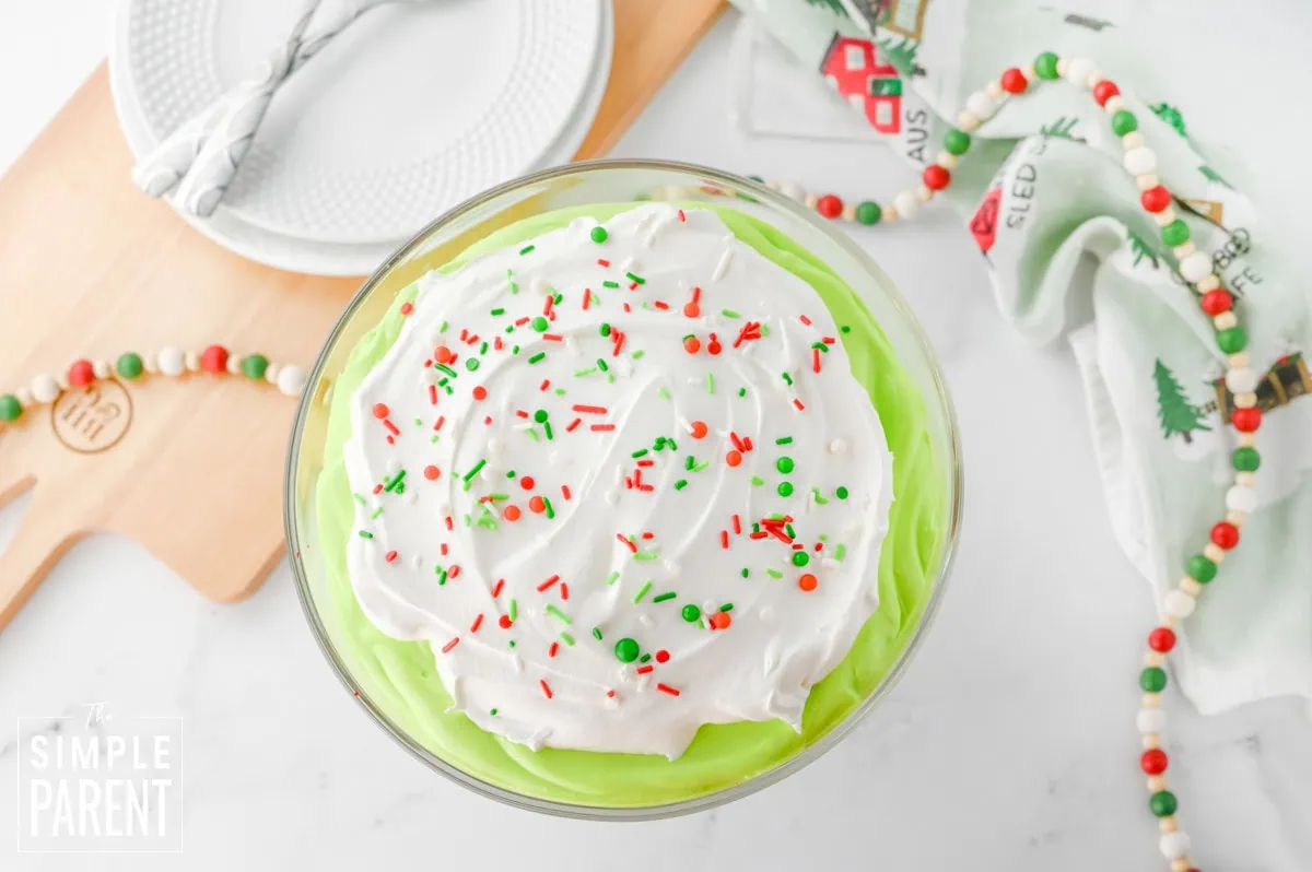 Grinch Trifle in glass bowl on white counter and Christmas garland