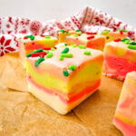 Squares of holiday white chocolate fudge on brown parchment paper