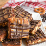 Stack of salted caramel pretzel bark on white plate with red and white plaid napkin