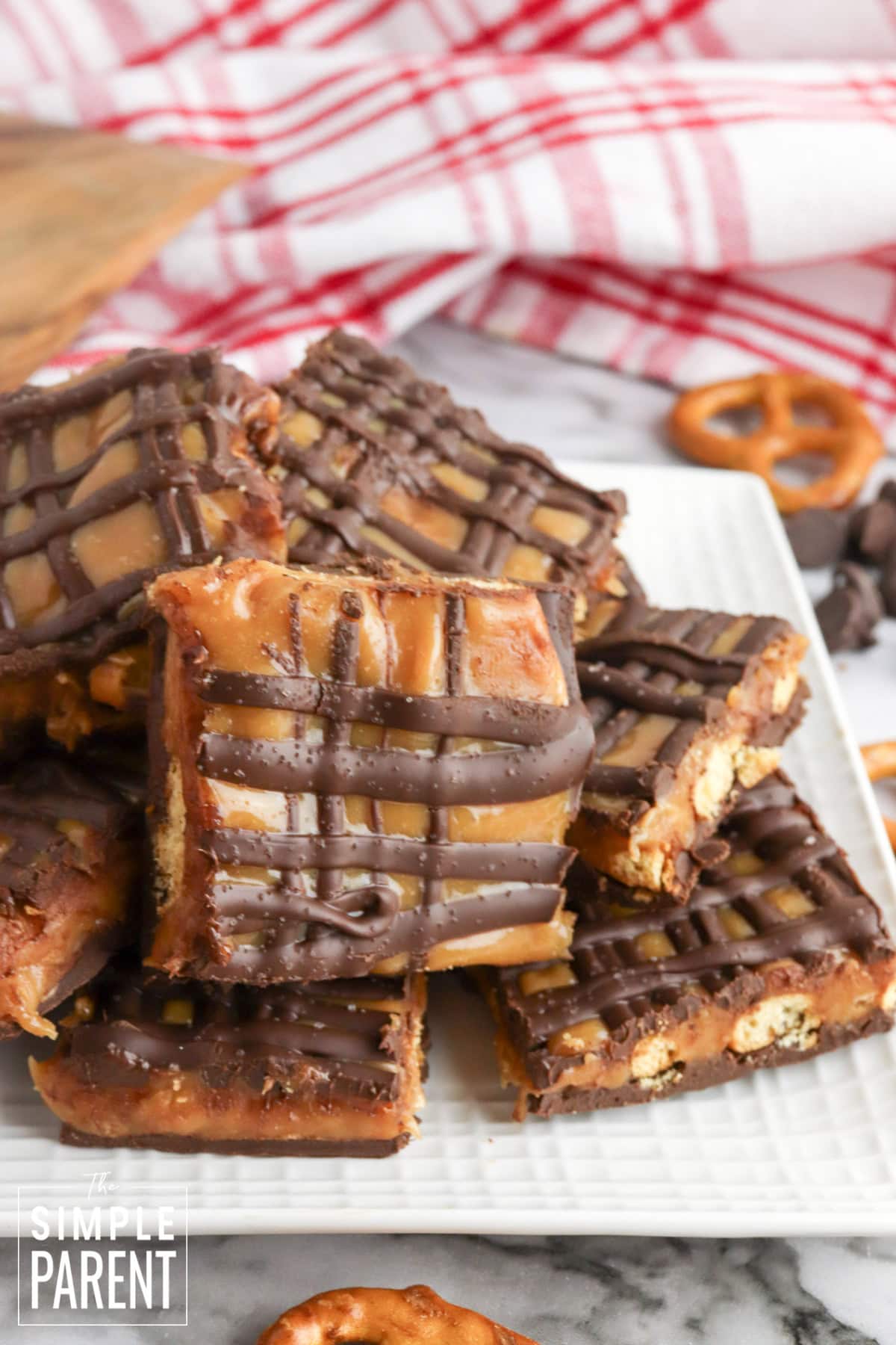 Stack of salted caramel pretzel bark on white plate with red and white plaid napkin