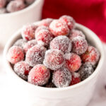 White bowl of sugared cranberries on white counter