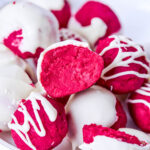 Red velvet cake balls with white icing in white bowl