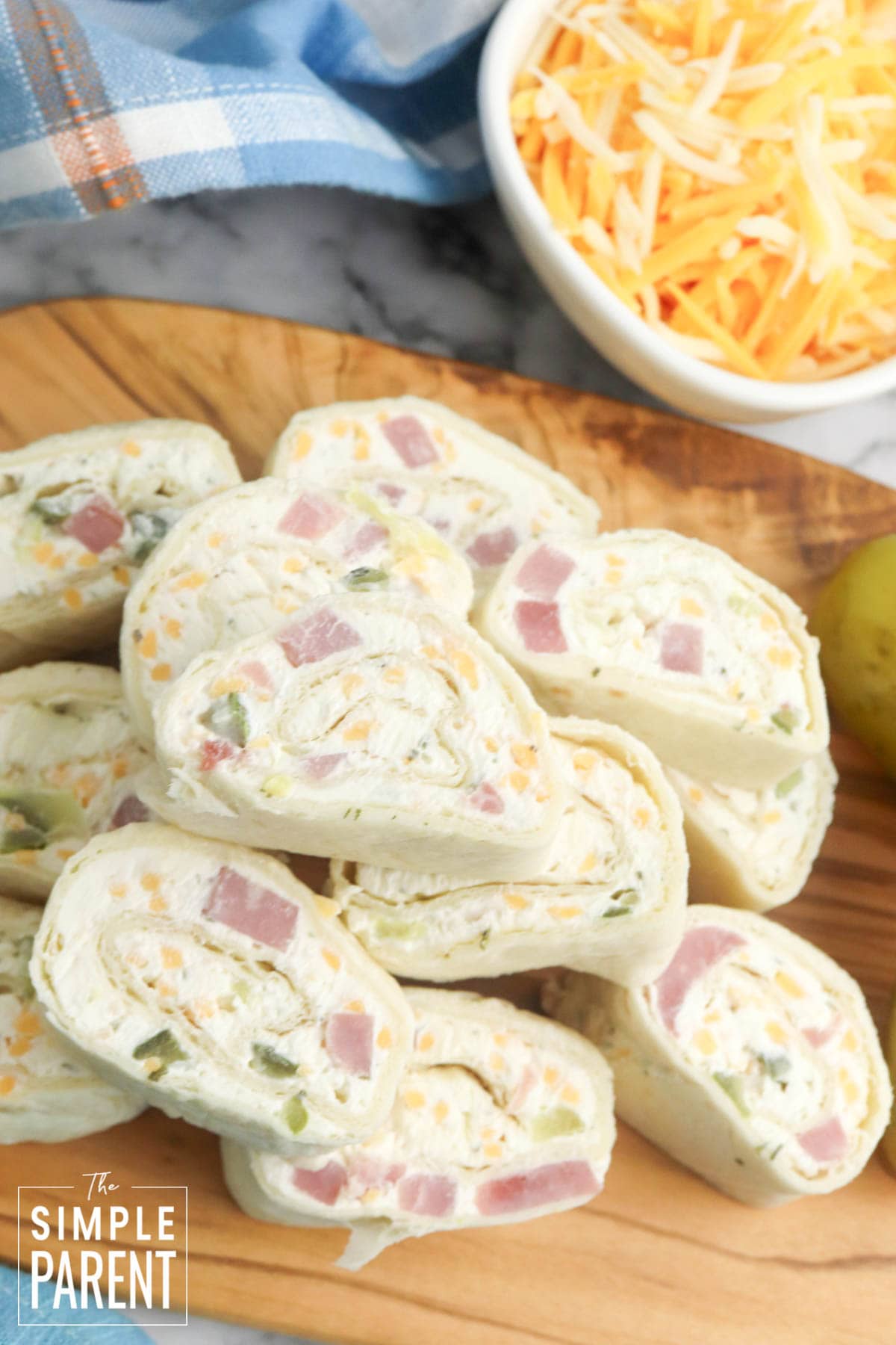 Stack of ham and cheese pinwheels on wooden serving board
