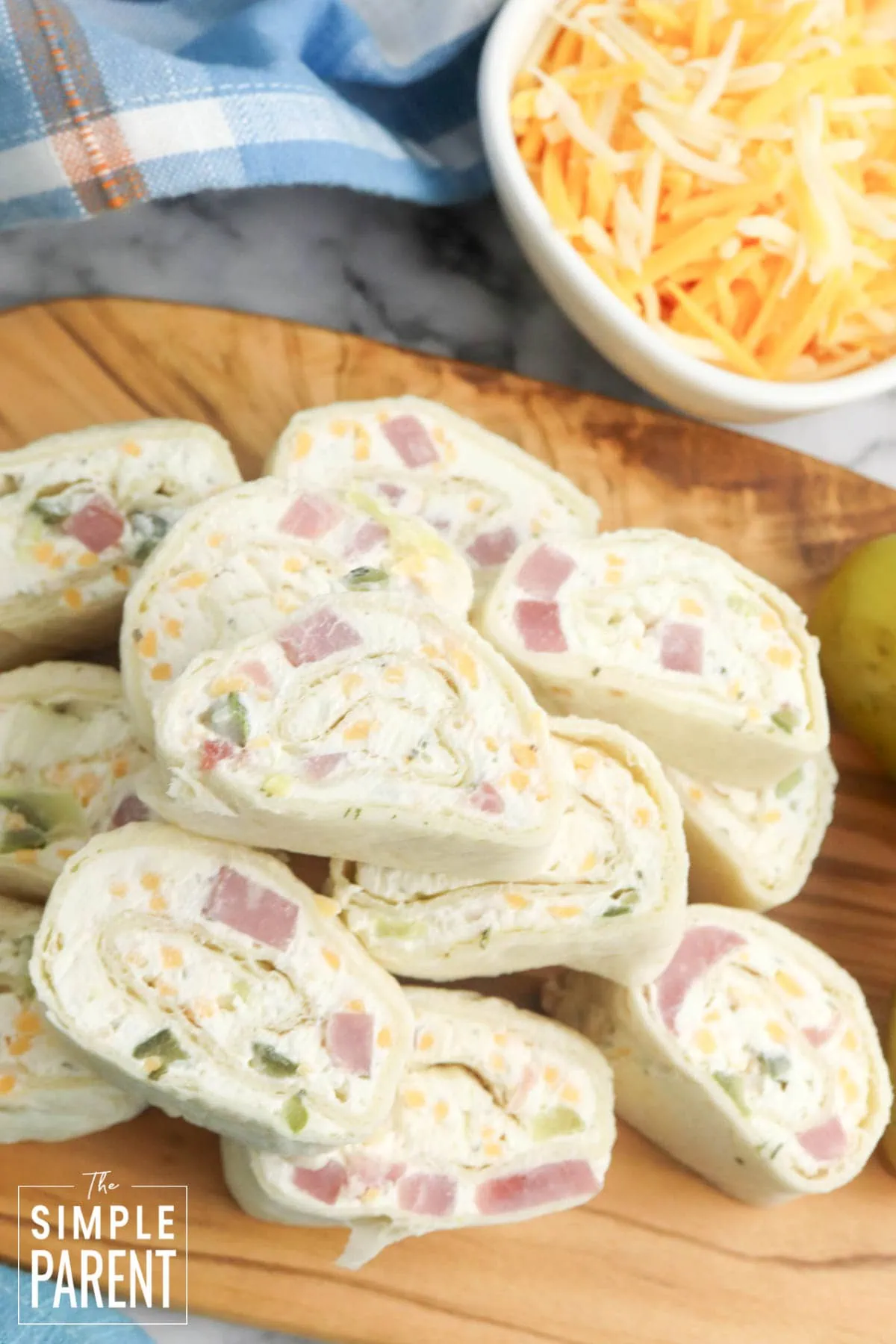 Stack of ham and cheese pinwheels on wooden serving board