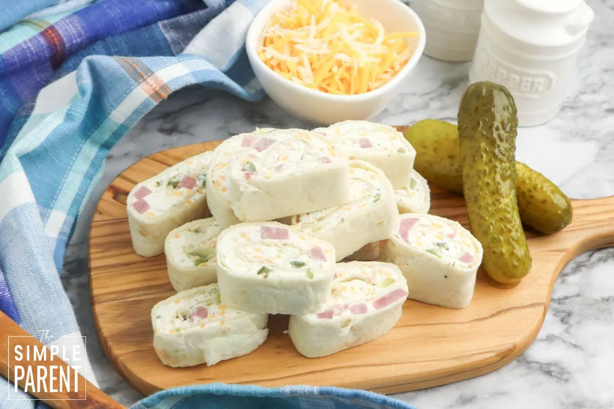 Stack of ham and cheese roll ups on wooden cutting board