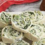 Stack of spinach pinwheels on white plate with red napkin