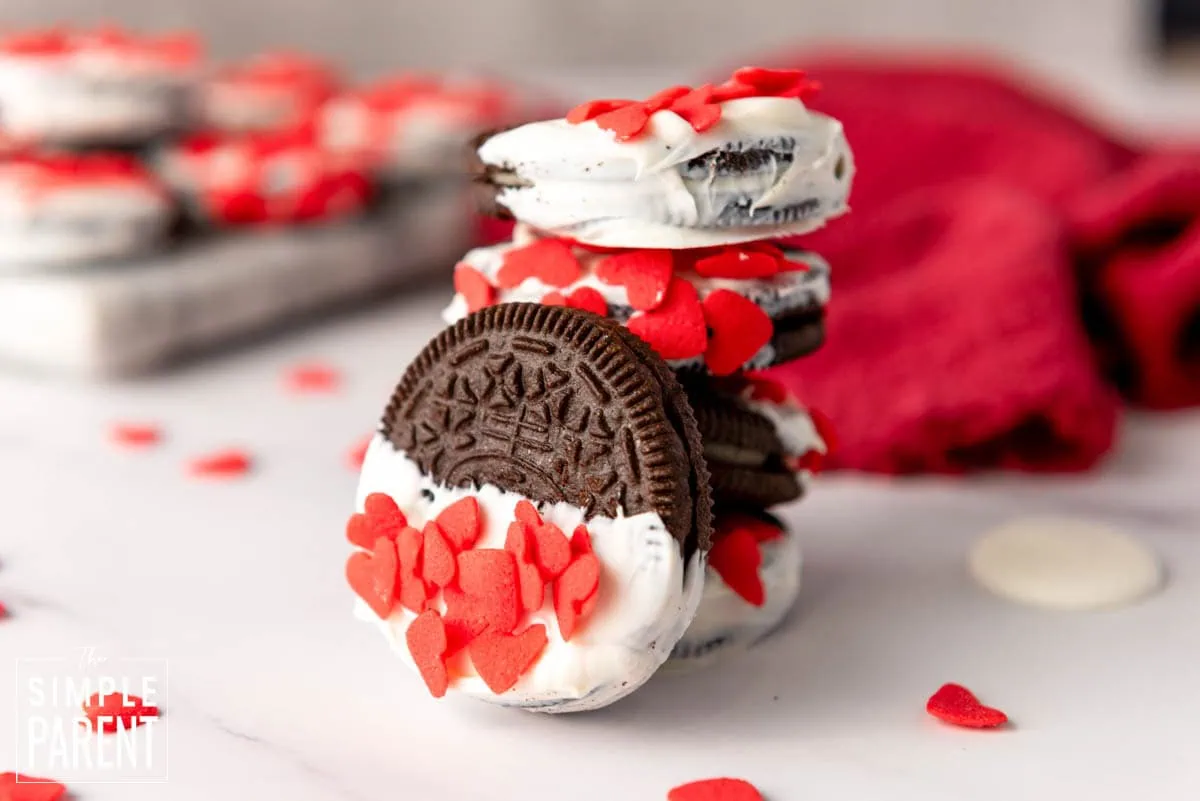 Decorated oreos with Valentine's Day red sprinkles stacked on white counter