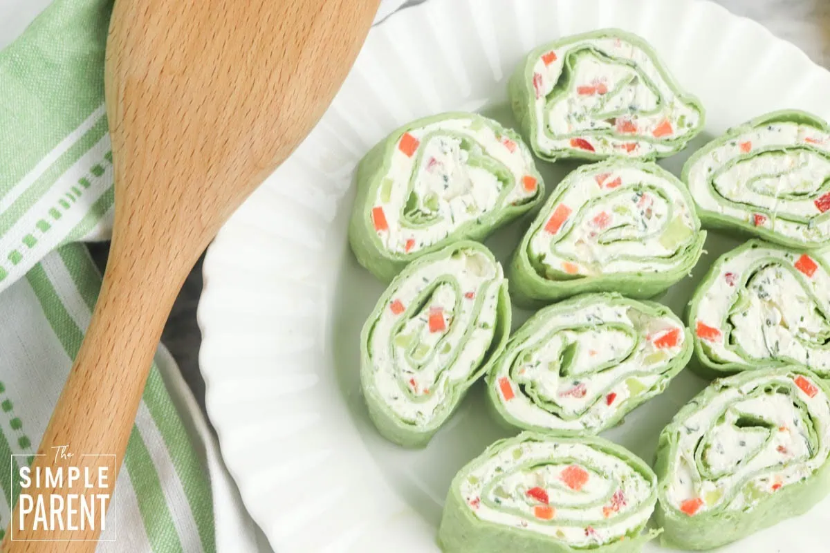 Vegetable pinwheels on white plate with a wooden spoon
