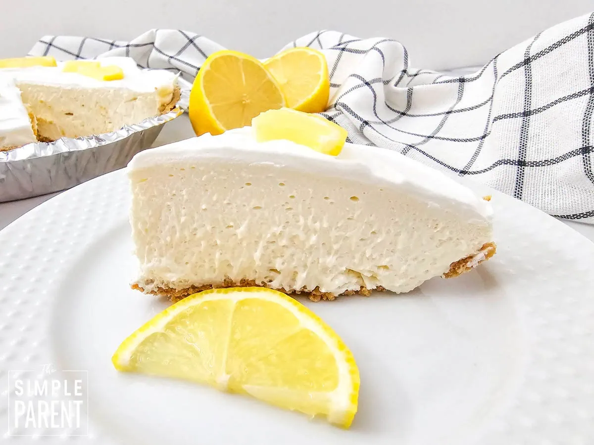 Slice of lemon pudding pie with lemon slice on white plate
