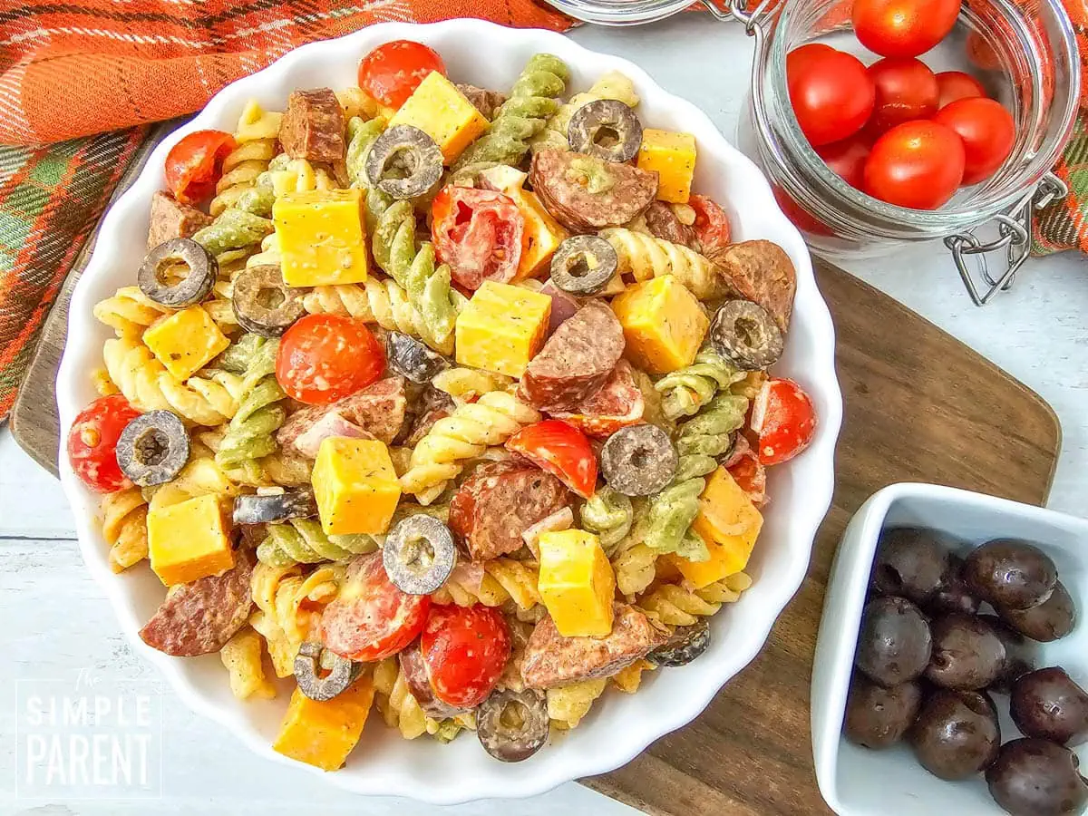 smoked sausage pasta salad in white bowl on wooden cutting board