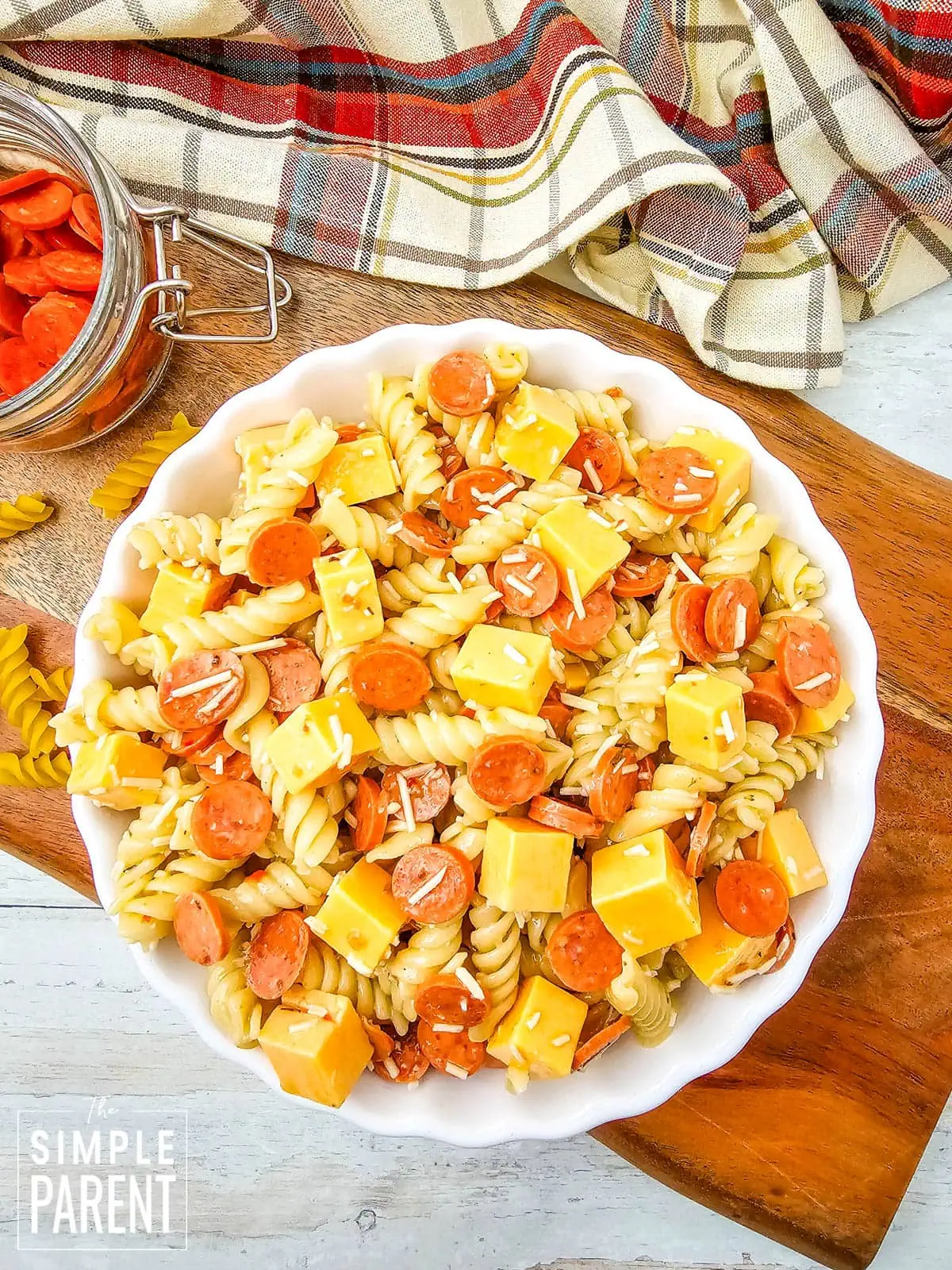 italian pasta salad with pepperoni in white serving bowl on wooden cutting board