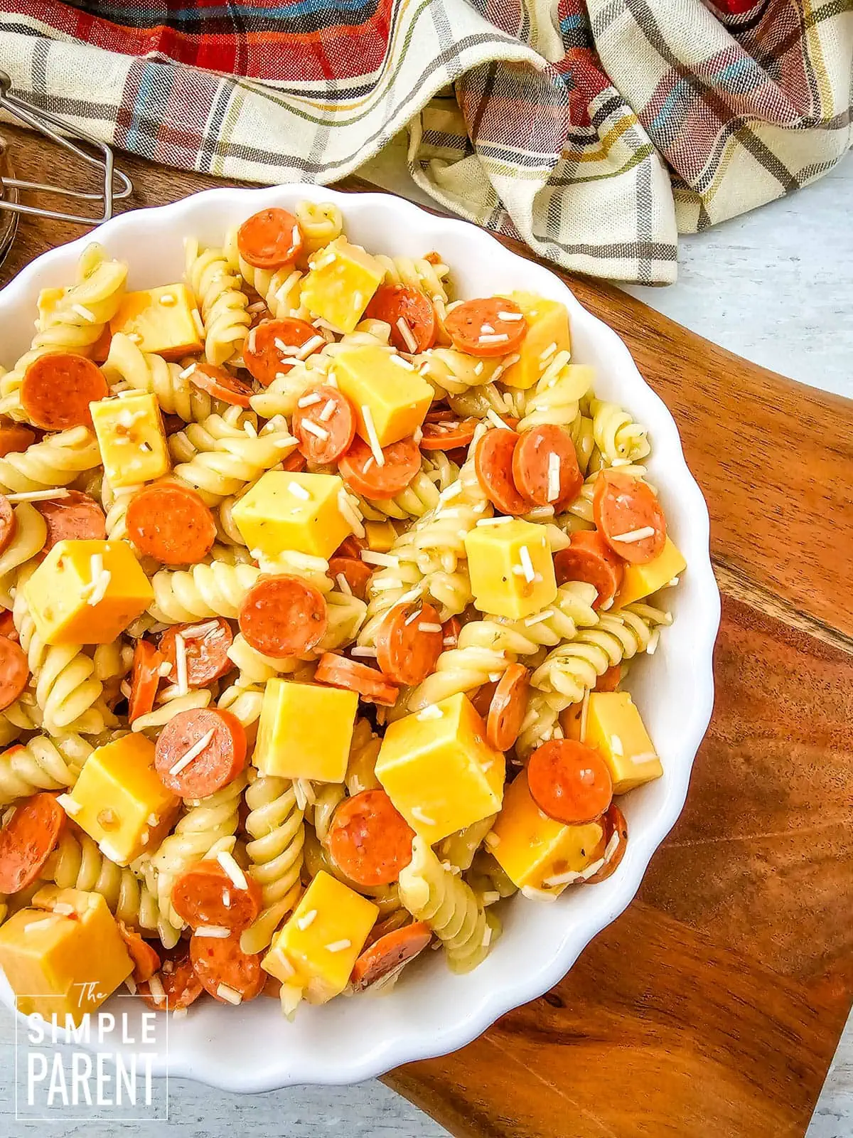 Pepperoni and Cheese Pasta Salad in white bowl on wood cutting board
