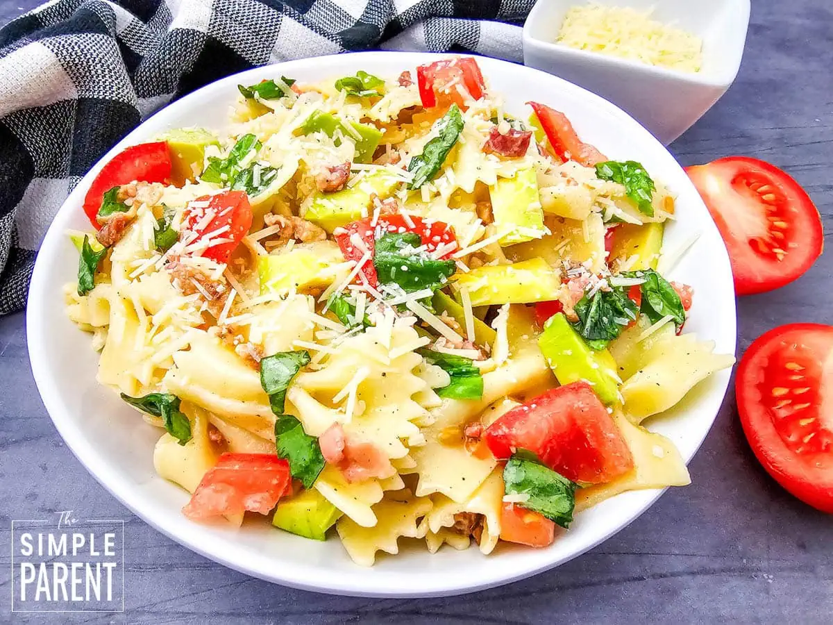 bacon avocado pasta salad in white plate on dark counter