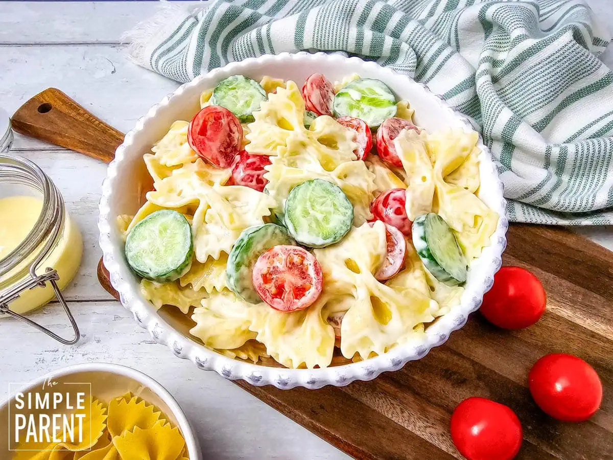 Cold bowtie pasta salad in white bowl with tomatoes and cucumbers