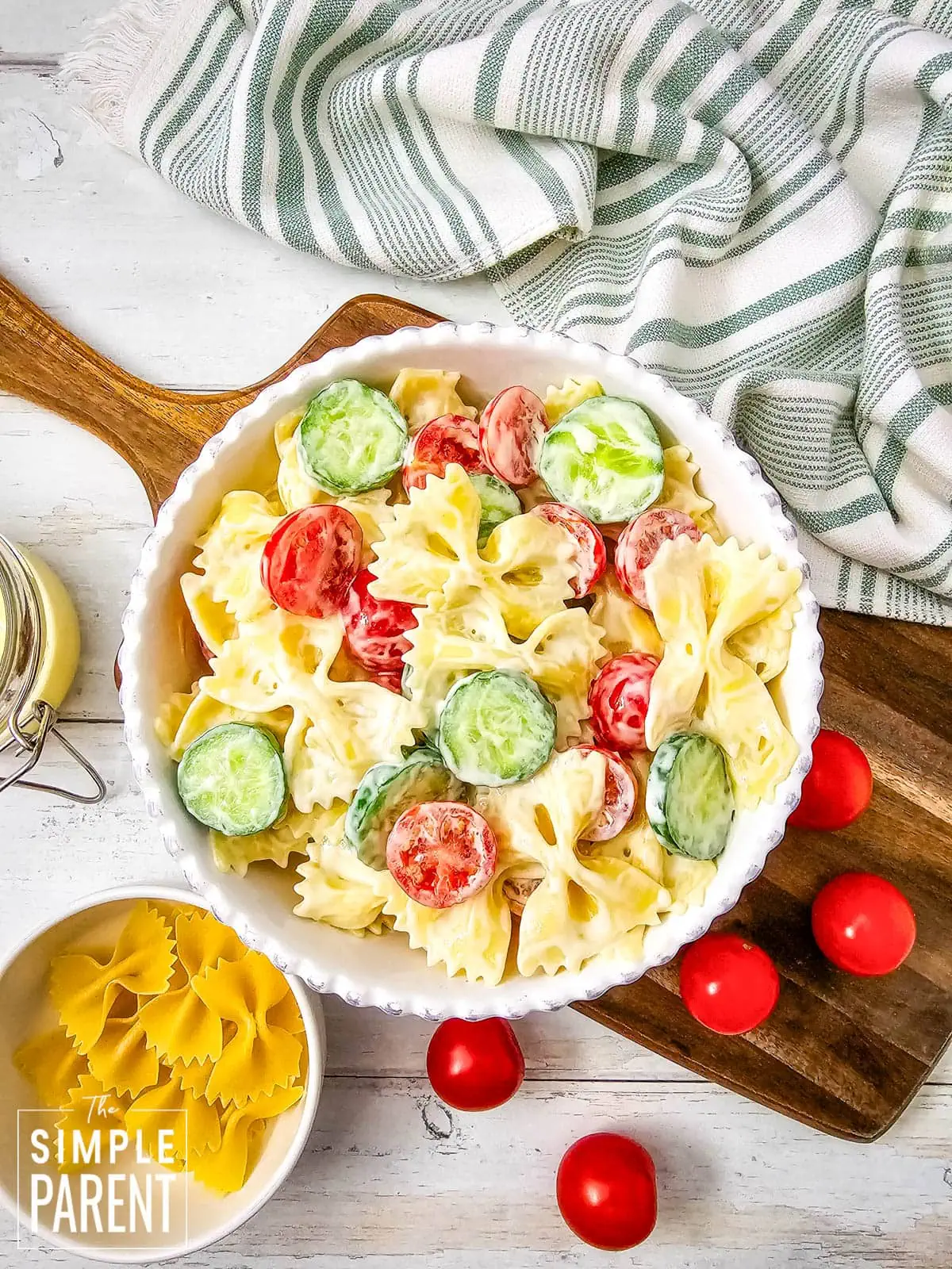 creamy bow tie pasta salad in white bowl on wooden cutting board