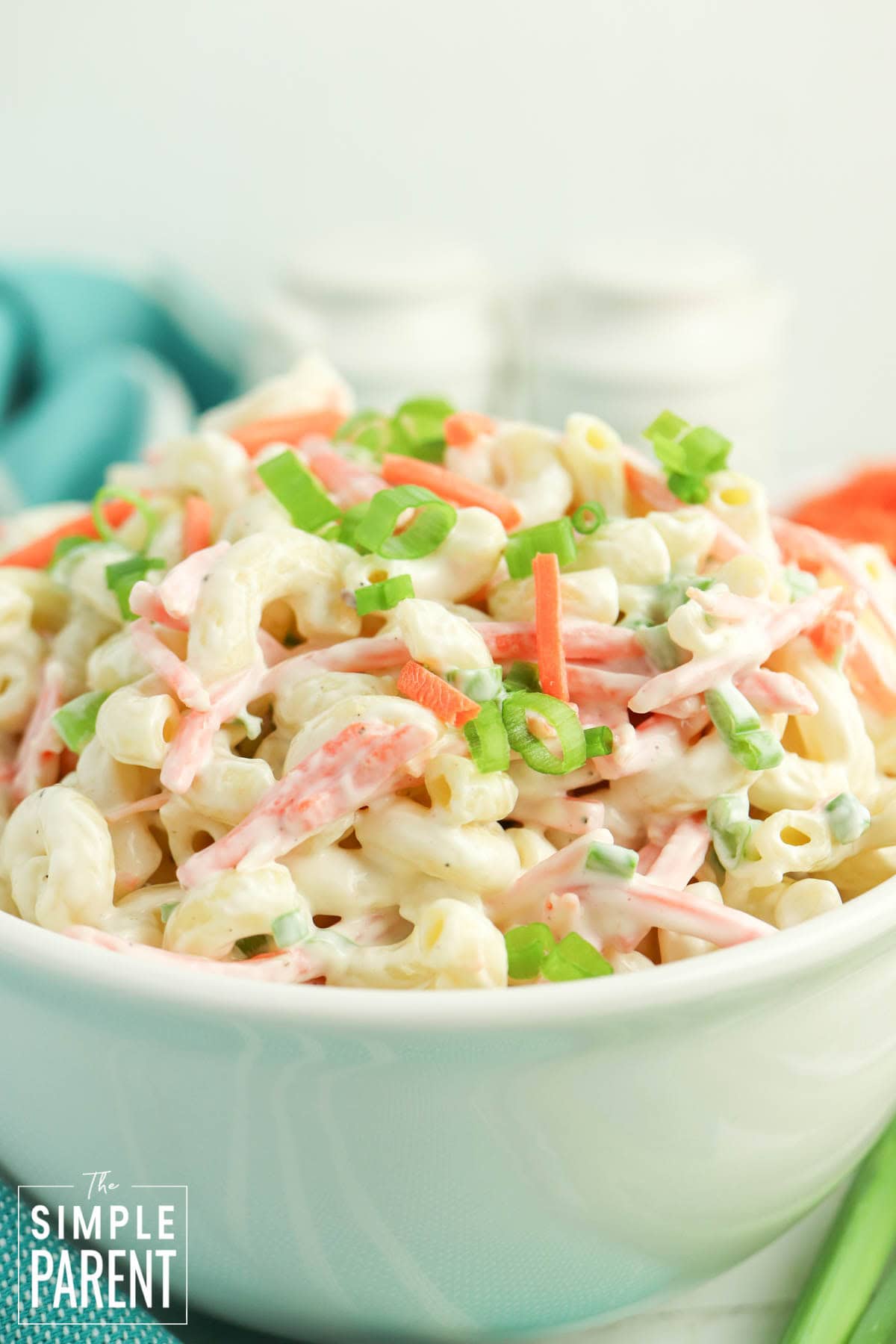 creamy macaroni salad in white bowl with aqua dishcloth